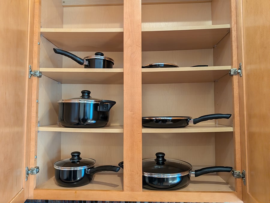 Kitchen: Fully stocked kitchen cabinet loaded with complete cookware-including non-stick frying pans, saucepans, and stockpots with lids. Ready for home-cooked meals!