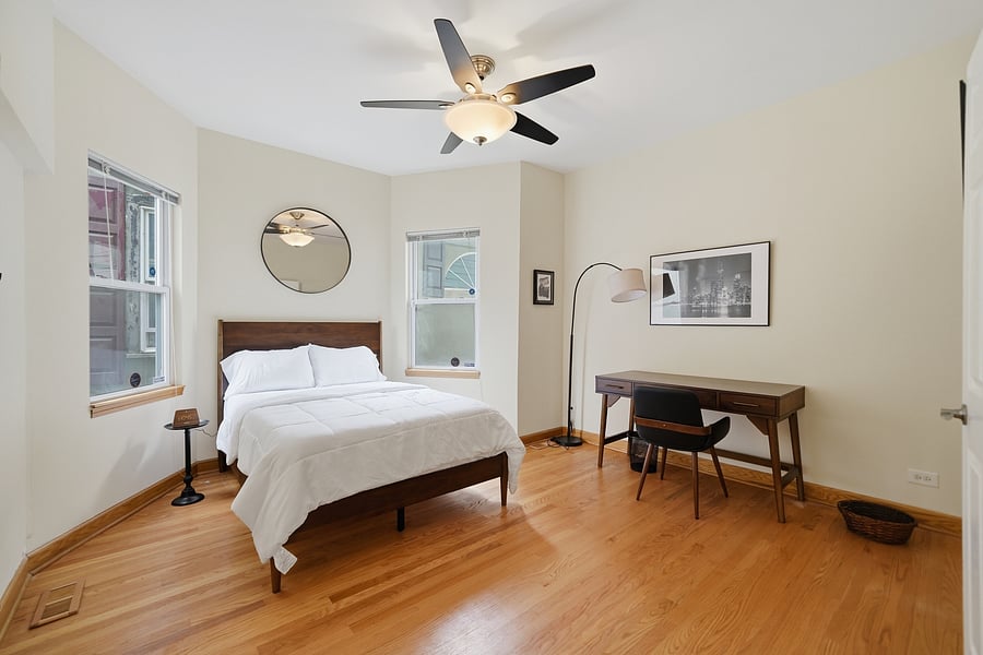 Bedroom: Serene, sunlit bedroom boasting a comfortable full size bed, ceiling fan, and a dedicated executive desk setup-ideal for remote work, telehealth, or studying.