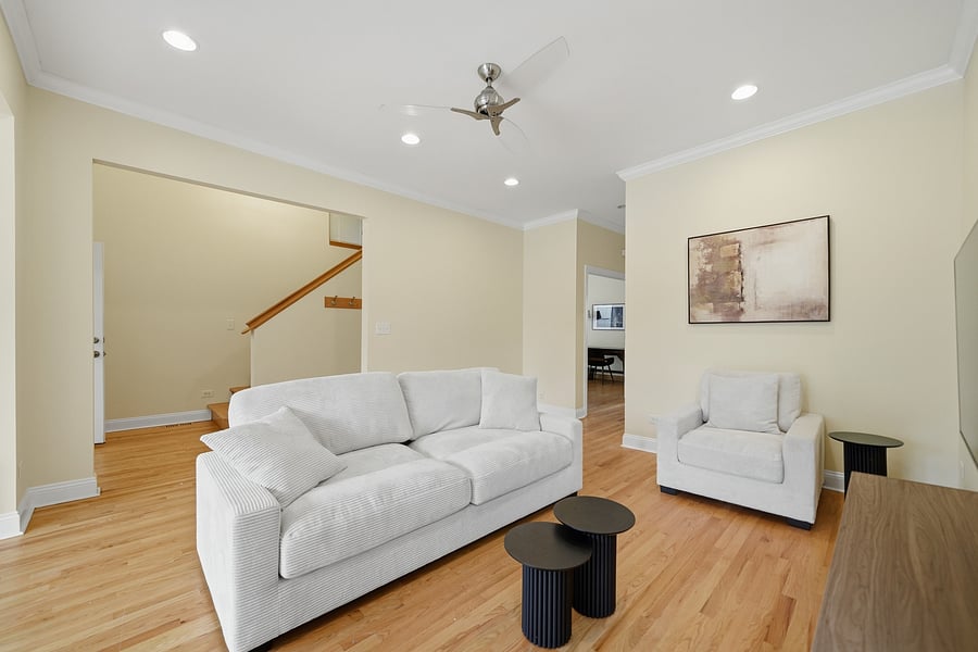 Living Room: Light-filled living room featuring gleaming hardwood floors with recessed lighting, modern neutral furnishings, and a wall-mounted TV. Perfect for unwinding after a shift.