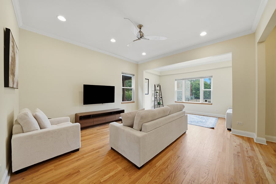 Living Room: Light-filled living room featuring gleaming hardwood floors with recessed lighting, modern neutral furnishings, and a wall-mounted TV. Perfect for unwinding after a shift.