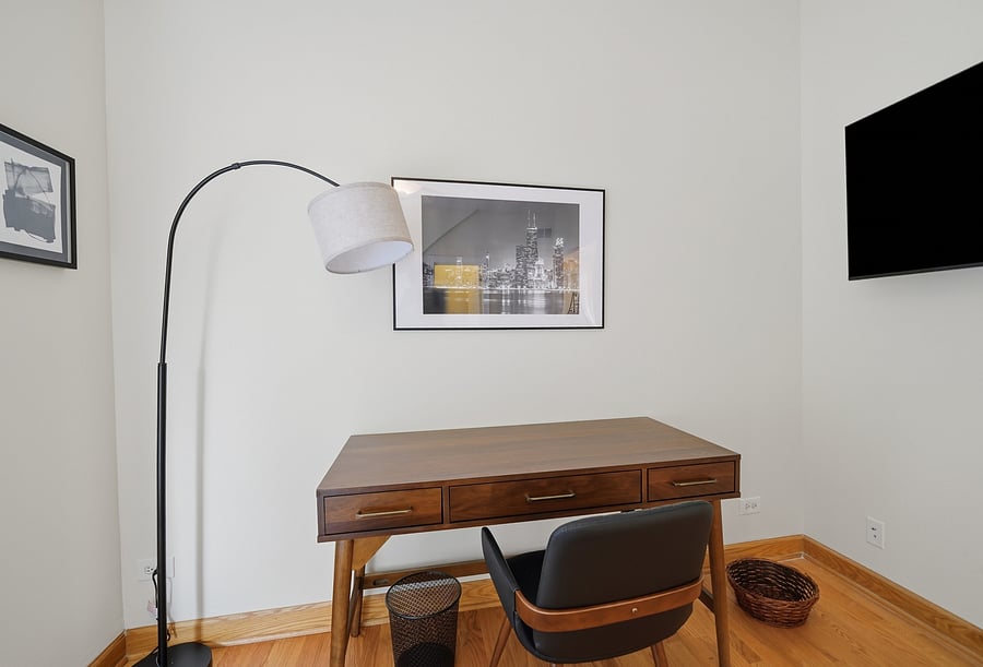 Bedroom: Dedicated executive workspace featuring a rich wood desk, ergonomic desk chair, arc floor lamp, and wall-mounted Smart TV-perfect for remote work, telehealth, or studying.