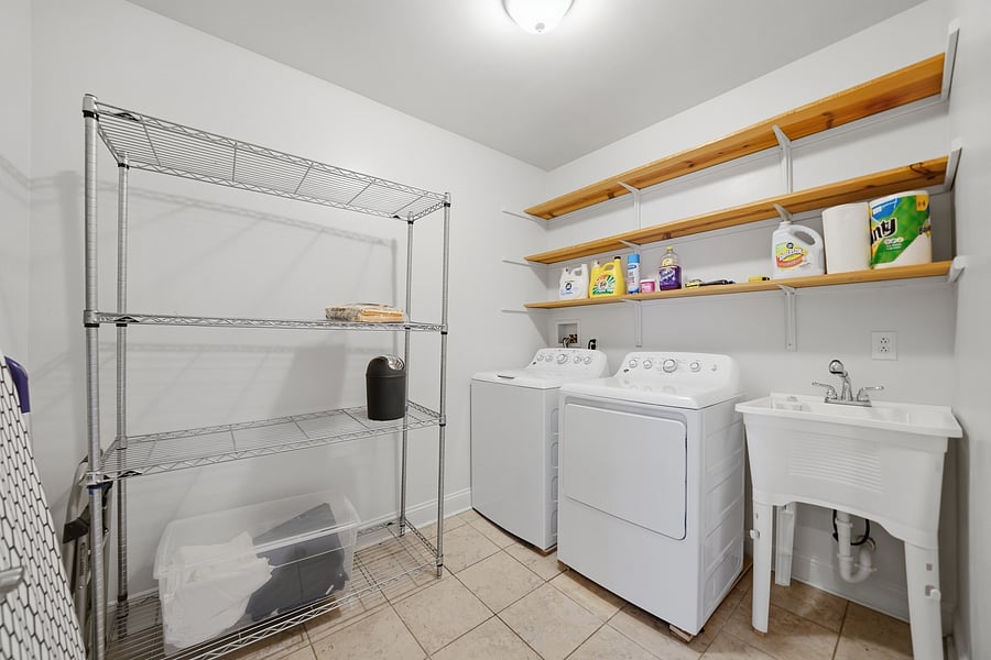 Laundry: Huge dedicated laundry and utility room inside the unit, complete with a full-sized washer/dryer, laundry utility sink, and extensive wire shelving for extra storage.