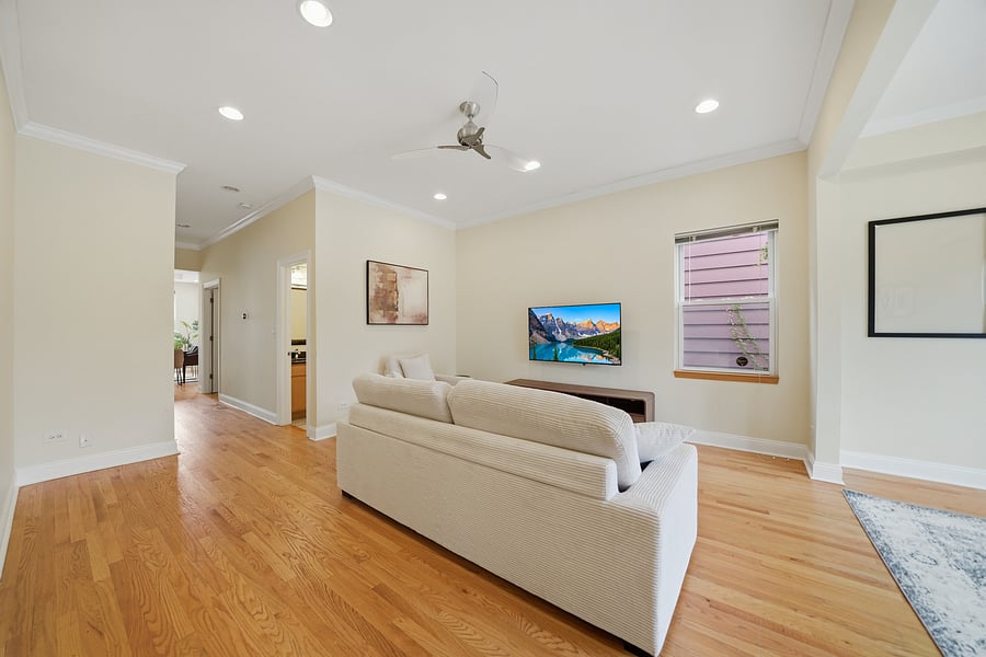 Living Room: Light-filled living room featuring gleaming hardwood floors with recessed lighting, modern neutral furnishings, and a wall-mounted TV. Perfect for unwinding after a shift.