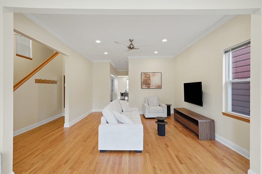Living Room: Light-filled living room featuring gleaming hardwood floors with recessed lighting, modern neutral furnishings, and a wall-mounted TV. Perfect for unwinding after a shift.