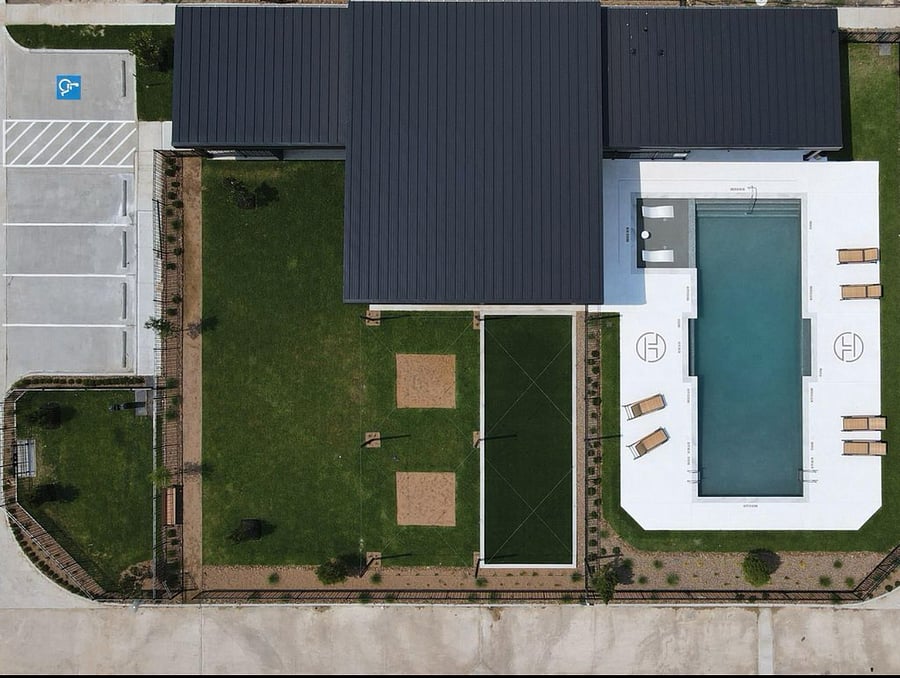 Aerial view of the pool, lawn, and outdoor lounge areas.