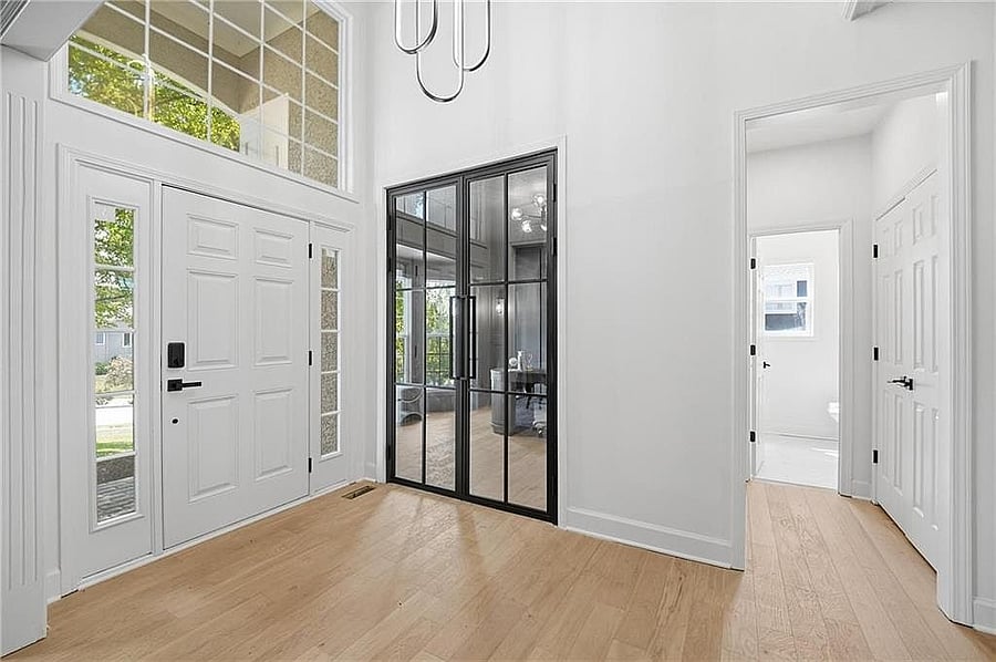 Two-story foyer with wood floors and glass-door office off the entry