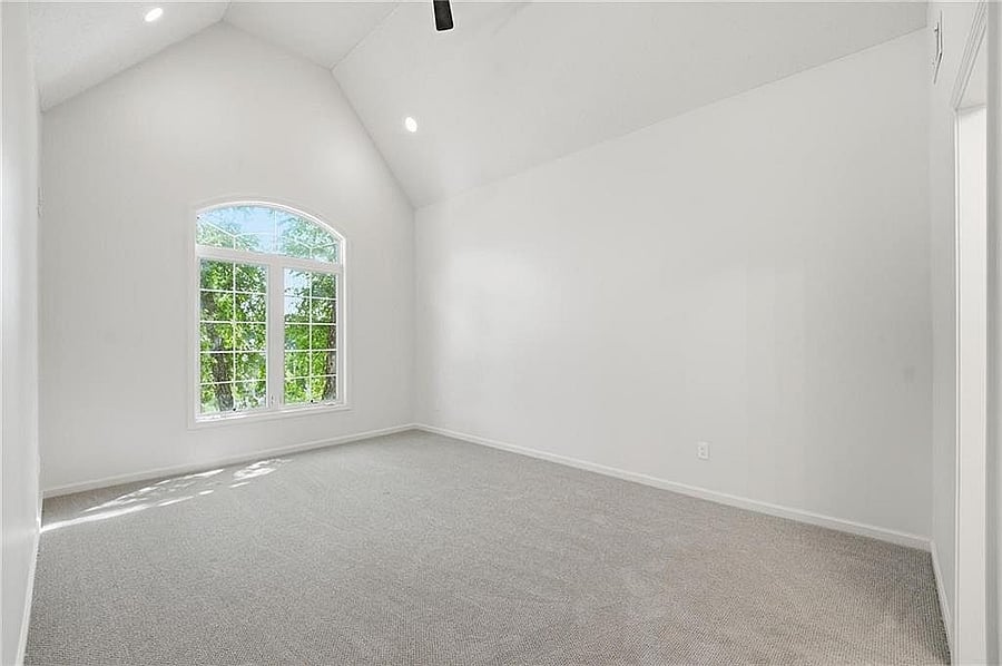 Upstairs bedroom with vaulted ceiling and arched window