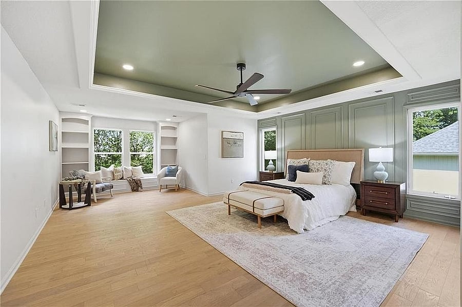 Primary bedroom with tray ceiling, ceiling fan and hardwood floors