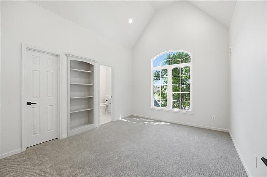 Upstairs bedroom with vaulted ceiling and built-in closet shelves