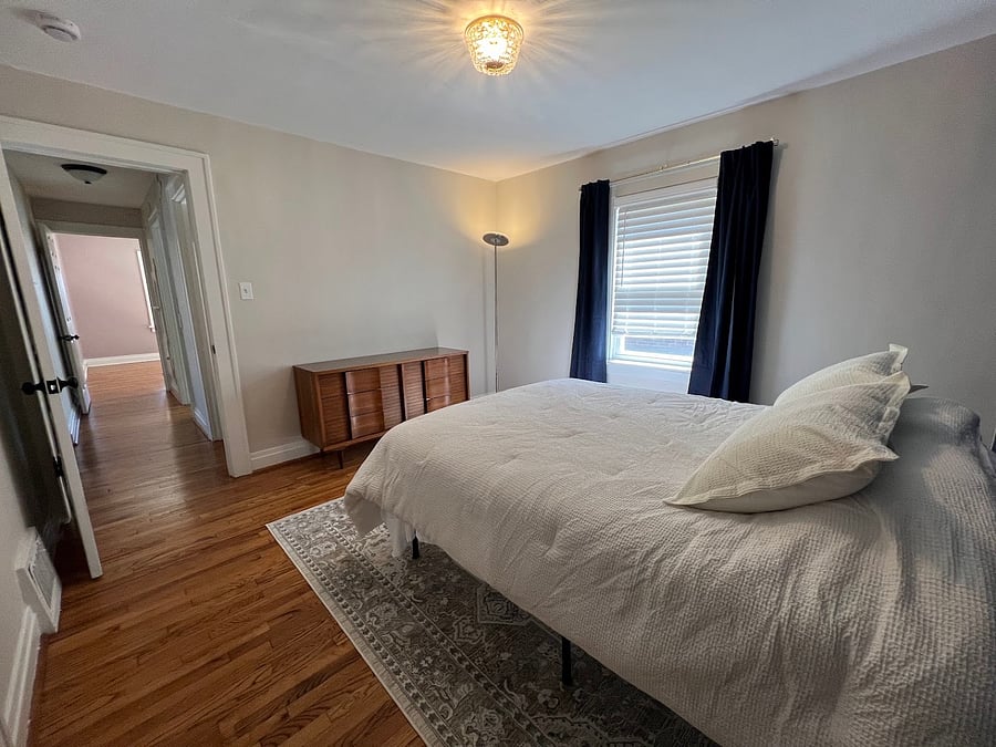 Main floor bedroom with queen-size mattress. Blackout curtains and blinds for the window treatments. The closet is on the left side of this picture. Additional storage space under the bed frame.