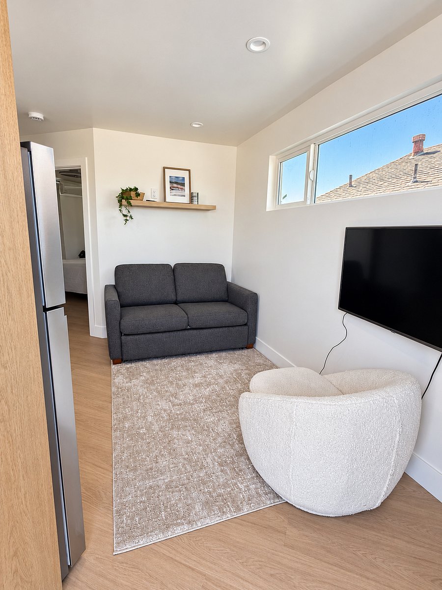 living area with pull out sofa, swivel chair and mounted swivel smart tv
