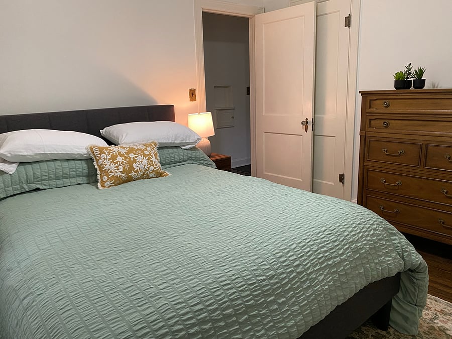 Secondary bedroom with queen bed, closet, tall dresser.