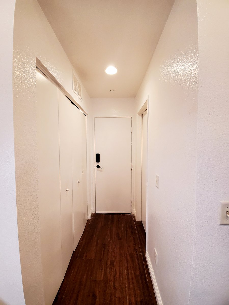 Hallway featuring the laundry room door on the left, the guest half-bathroom door on the right, and direct access to the attached garage at the end of the hallway.
