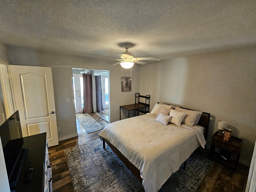 Primary bedroom with dual closets with sliding mirror doors, and French doors to front patio with blackout curtains.