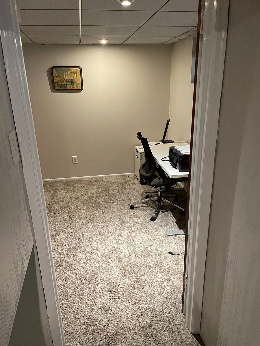Office space located in basement offers an adjustable desk, bookcase and day trundle bed.