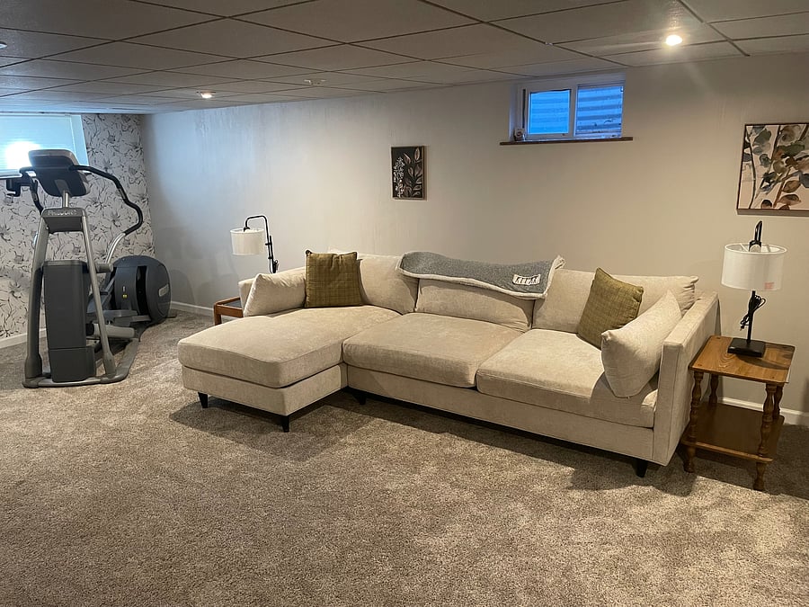 Family room located in fully finished basement complete with sofa, bean bag chair, 52" smart TV and Procor ellipical