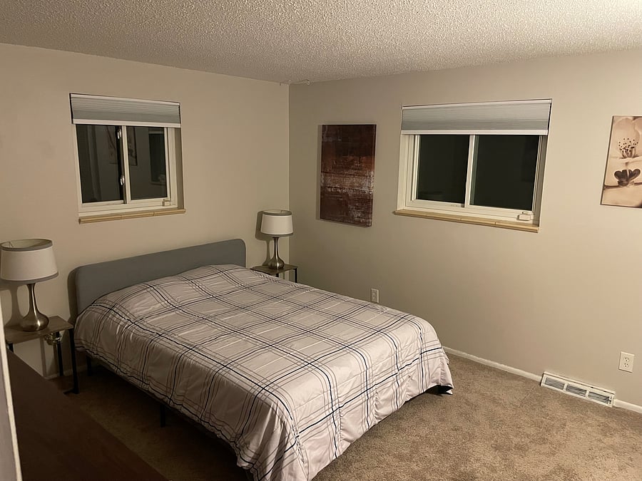 Mainfloor bedroom #1 furnished with a comfortable queen bed, full dresser and two clothes closets. Windows look out to back porch and yard.