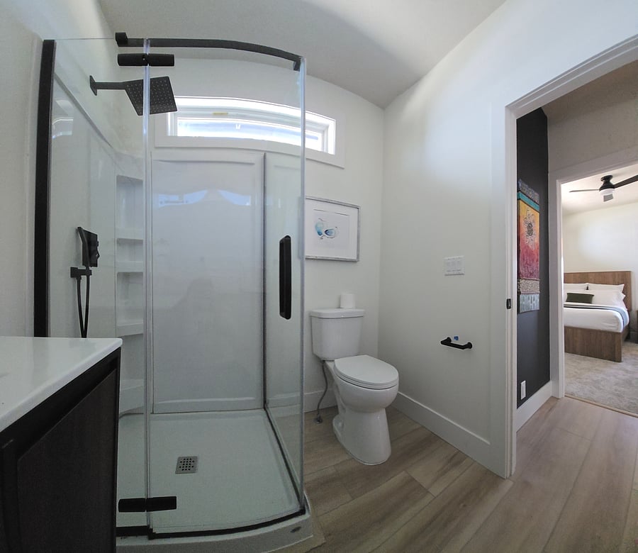 Main level bathroom with modern black features, rain shower head, glass shower doors and toilet.