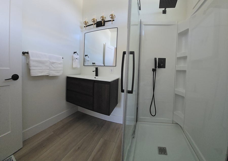 Main level bathroom with modern black features, rain shower head, glass shower doors and toilet.