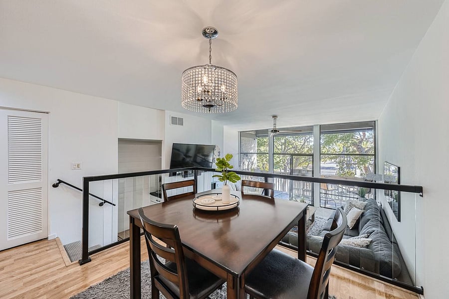 The dining area overlooks the lower living space, creating an open and connected layout while maintaining distinct areas for dining and relaxing.