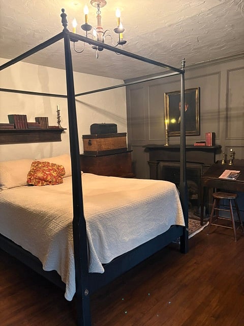 4 poster Qn bed next to a great realistic fireplace & Persian rugs make this Bed Chamber so special.