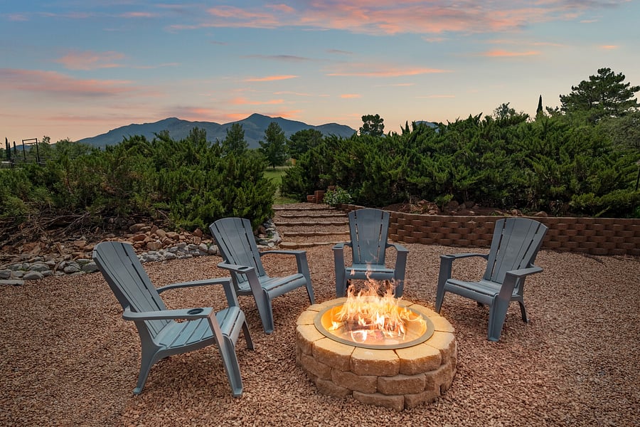 Outdoor fire pit with Adirondack chairs creates a welcoming gathering space beneath the mountain backdrop.