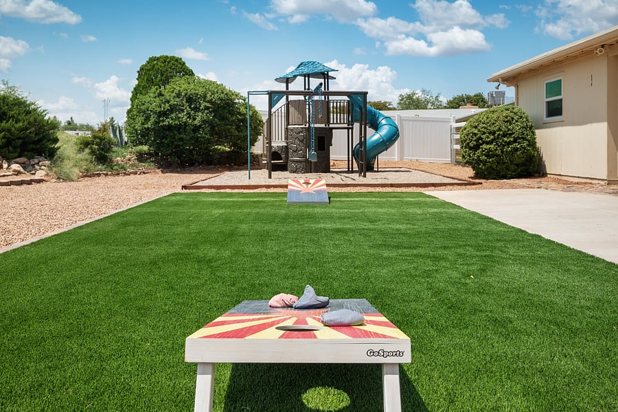 Enjoy a game of cornhole on the low-maintenance artificial turf lawn in the spacious backyard.