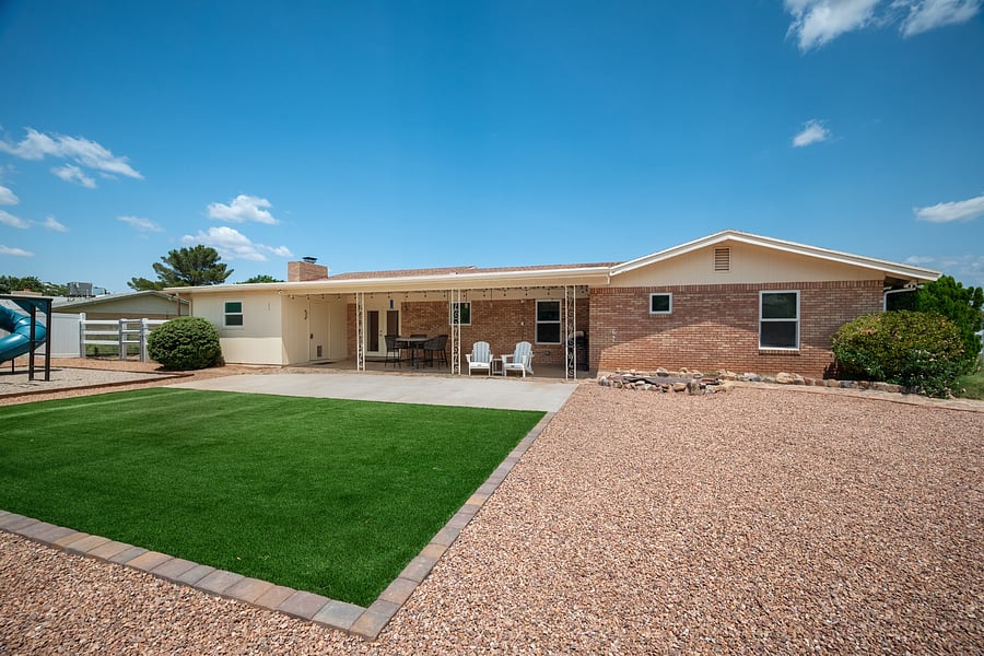 Private backyard with artificial turf and a covered patio for relaxing and enjoying time outdoors.