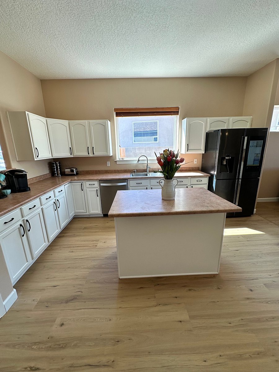 In the left corner is shown a spice spin rack and a toaster. Also pictured is the dishwasher and a large refrigerator with the freezer on the bottom.