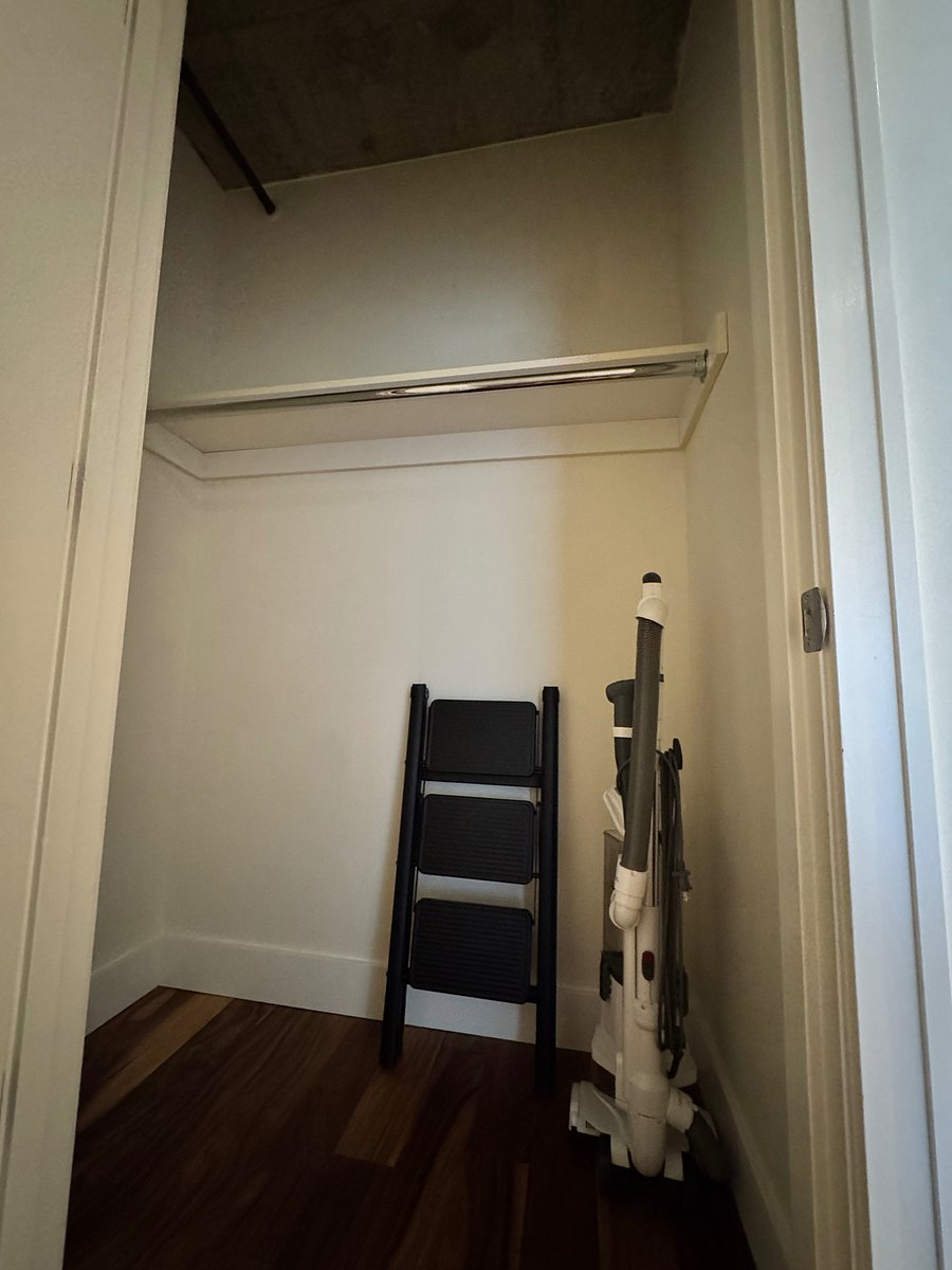 Vacuum and step stool in hall entry closet.