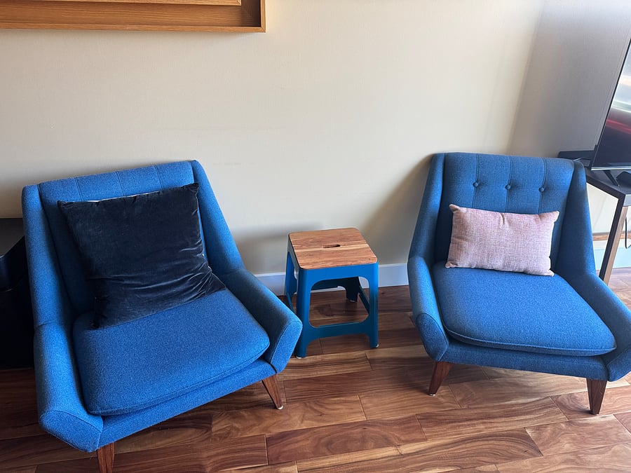 Low and wide midcentury modern fabric lounge chairs in peacock blue, with matching stool/side table.