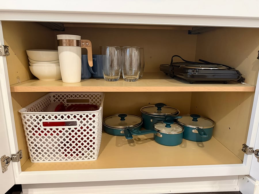 A fully stocked kitchen with bowls, plates, cups, mugs, glasses, pots and pans, and a hot plate, plus Tupperware and even a to-go mug for lunches on the run!