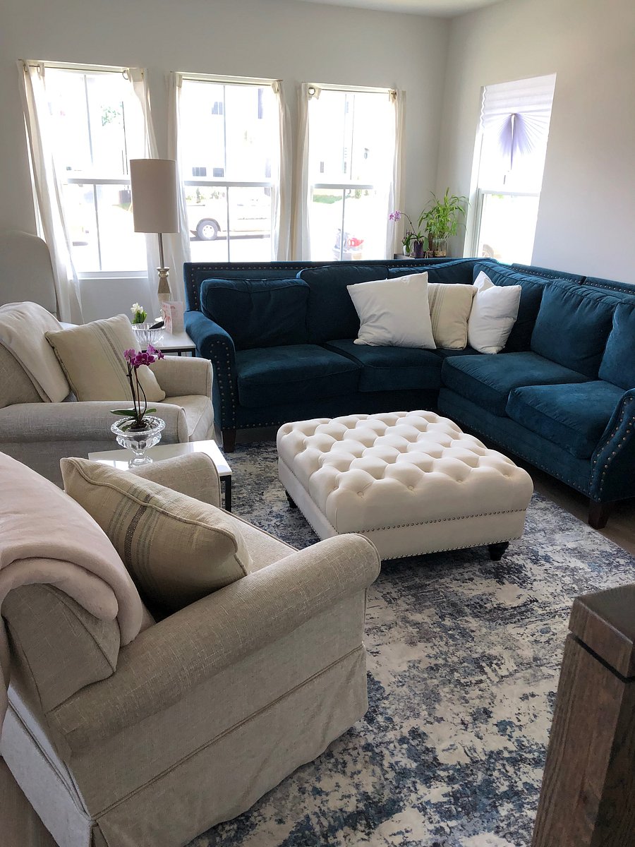 The living room is well-lit with beautiful daylight. There is a large TV mounted to the wall not seen and an electric fireplace beneath it (not pictured). I love decorating and I have several orchids that enjoy this sunlight.