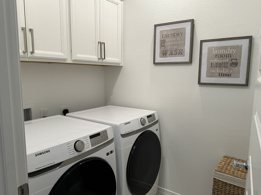 Laundry room with cabinets and full sized front loading washer and dryer.