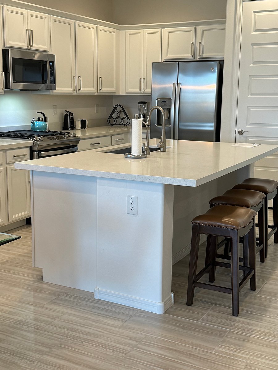 View of kitchen with breakfast bar stools, pantry in background, appliances, gas range, built in trash cans for a clean look and motion detector faucet turn on.
