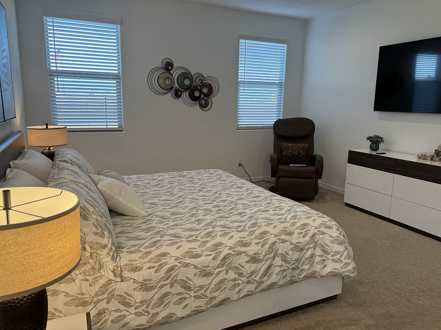 Second view of primary bedroom with relaxation chair that massages after a long day. Smart tv and dresser in view also.