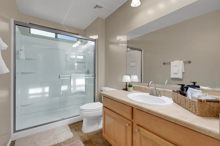 A bright, spa-inspired bathroom with a walk-in shower, plush white towels, and refillable bath essentials. (Includes: Shampoo, Conditioner, Body Wash, Hand Soap, Qtips, Cotton Pads)