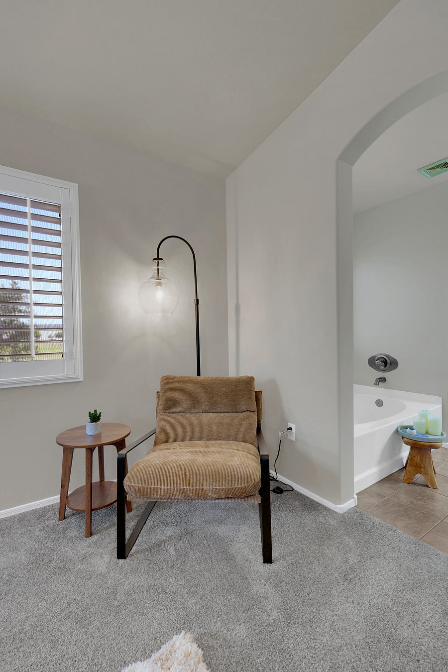 A peaceful reading nook with a statement floor lamp and easy access to the soaking tub.