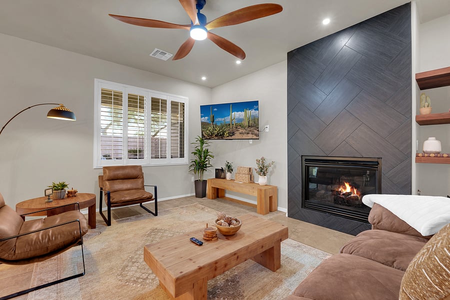 Kick back in the family room with a smart TV, modern ceiling fan, and a statement fireplace that sets a cozy mood.