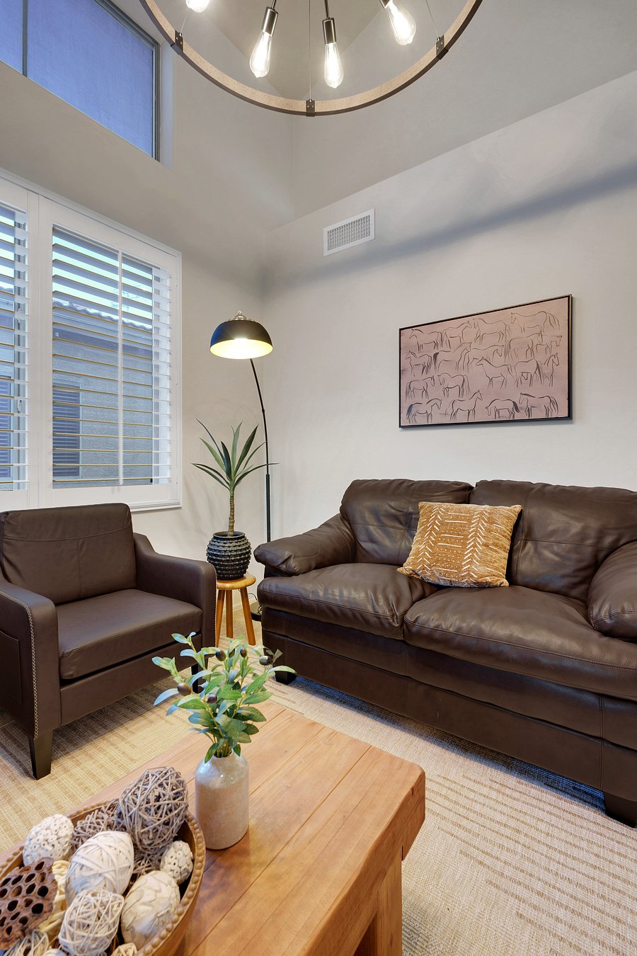 Curl up on the plush leather loveseat with warm lighting, soft textures, and stylish desert-inspired art.