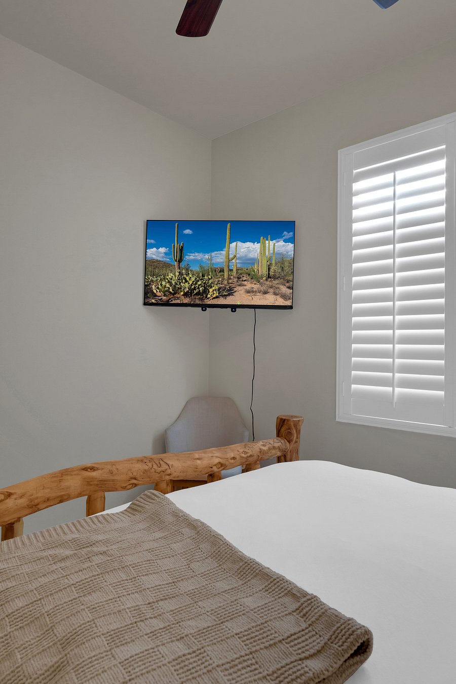 Unwind with a show from bed on the wall-mounted smart TV, with plantation shutters for easy light control.