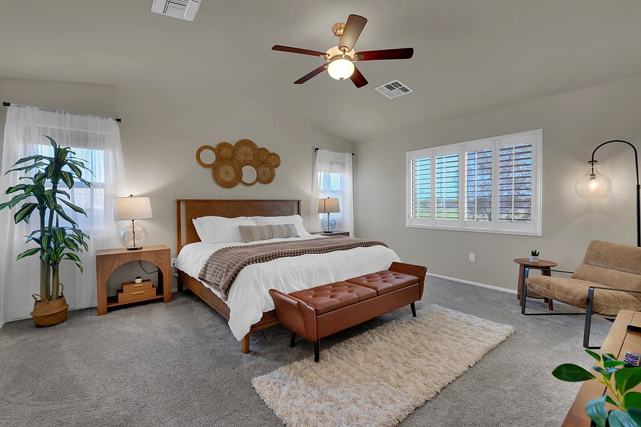Your luxe primary suite: a plush king bed, vaulted ceilings, and a cozy sitting area bathed in natural light.