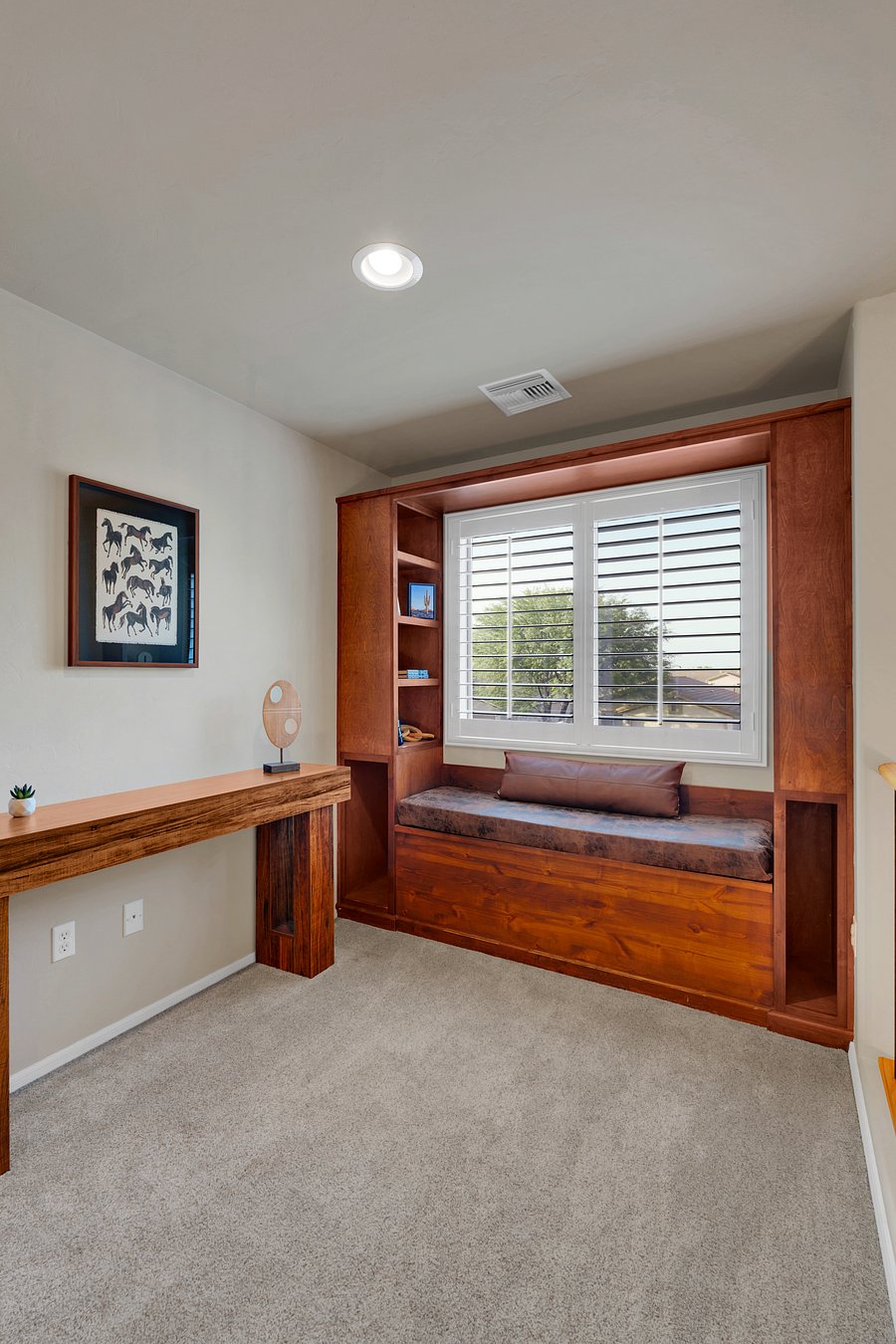 Curl up in the cozy library and reading nook, with a built-in window seat, custom wood shelving, and peaceful treetop views.