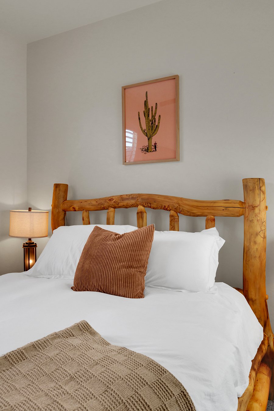 Sink into plush white bedding framed by a one-of-a-kind log headboard and playful saguaro art.