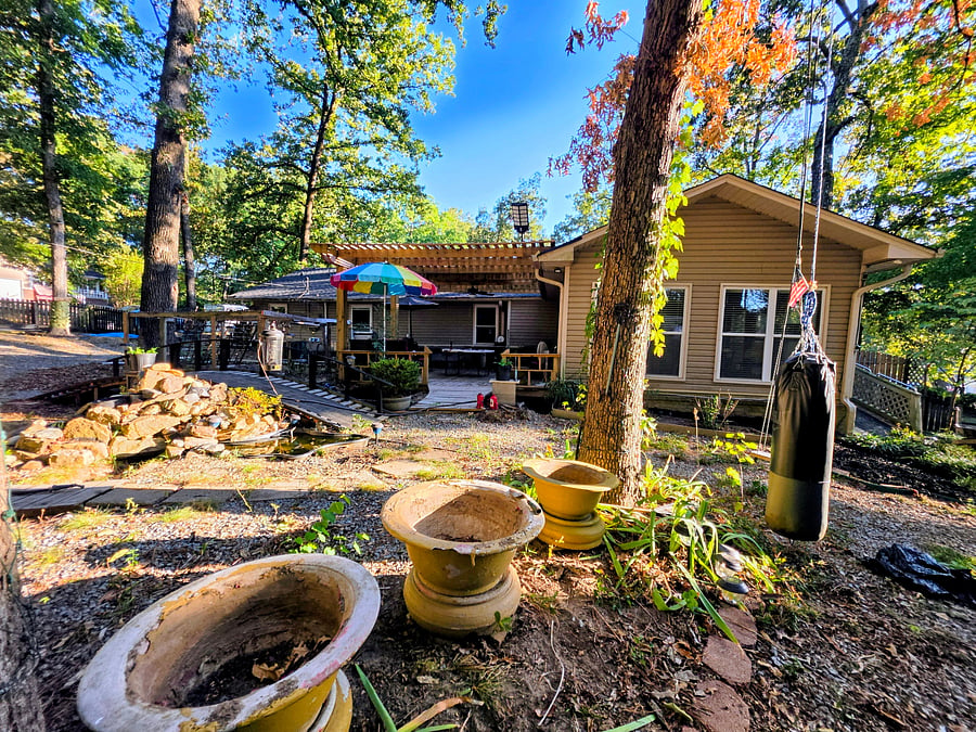 Outdoor deck, pond, grill and dining area surrounded by mature trees