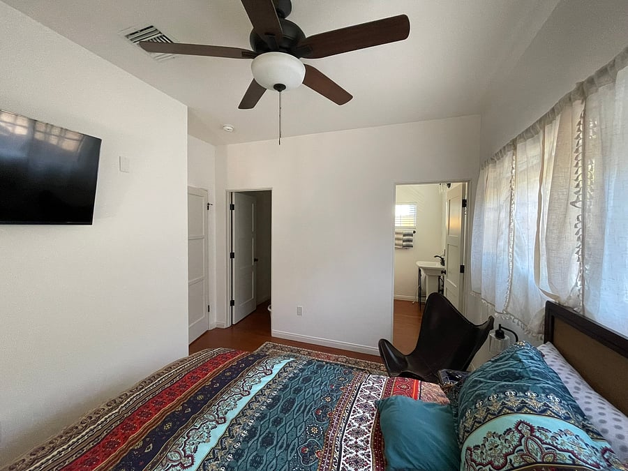 Light-filled en suite featuring classic architectural details, a Smart TV, a generous walk-in closet, a private 3/4 bath, and thoughtfully curated boho-inspired décor.