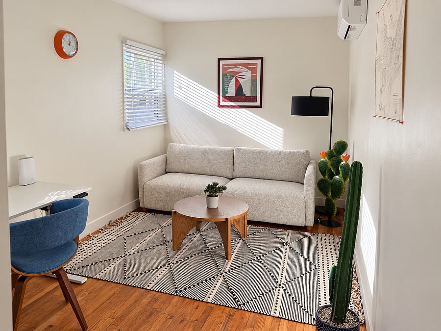 Flexible second bedroom featuring a queen sleeper sofa, dedicated workspace, lounge seating, and warm natural light. Perfect for work and occasional overnight guests.