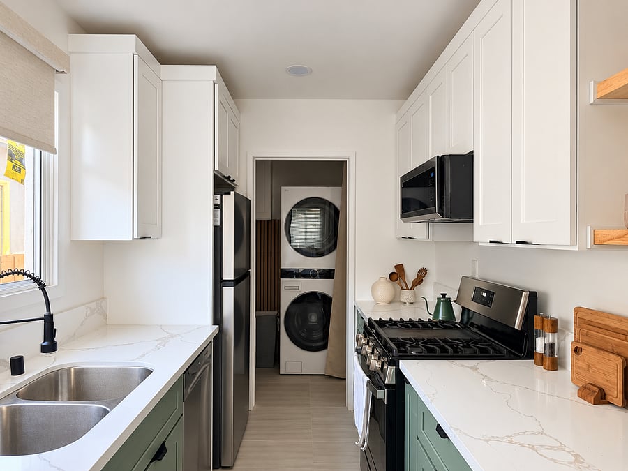 Beautiful galley kitchen with gas range, dishwasher, microwave, refrigerator, quartz countertops, and ample cabinetry for everyday cooking.