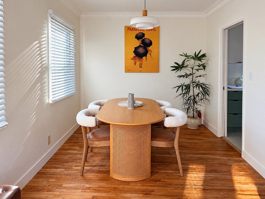 Dedicated dining room with warm wood table, four comfortable chairs, modern pendant lighting, and abundant natural sunlight.