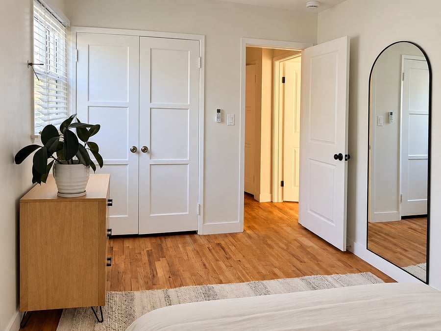 Primary bedroom with full-length mirror, spacious closet, wood dresser, and hardwood floors. Plenty of room to unpack and settle in.